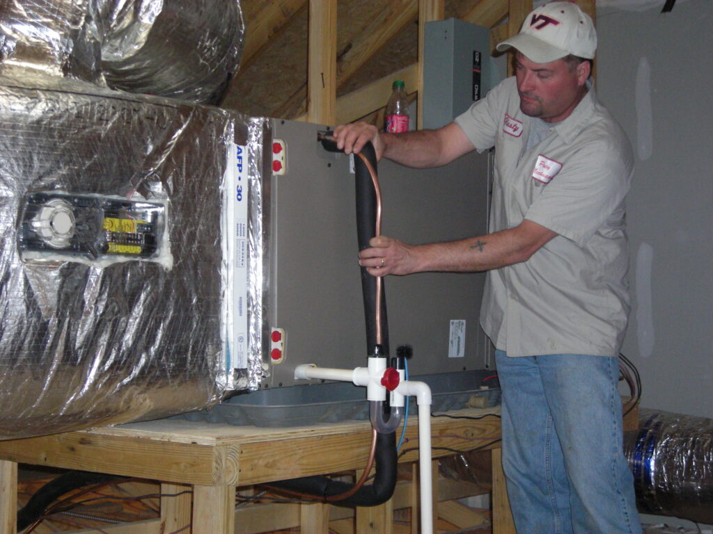 A Putney employee installs a cooling unit in a Farmville home.